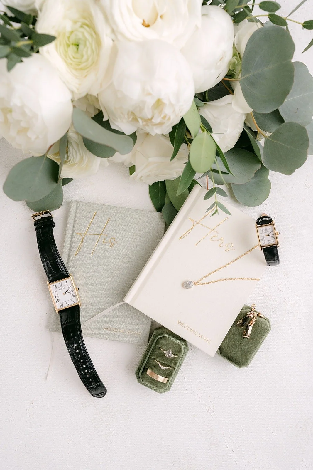 Vivian and Yao's flat lay with white roses, a green velvet ring box and matching watches