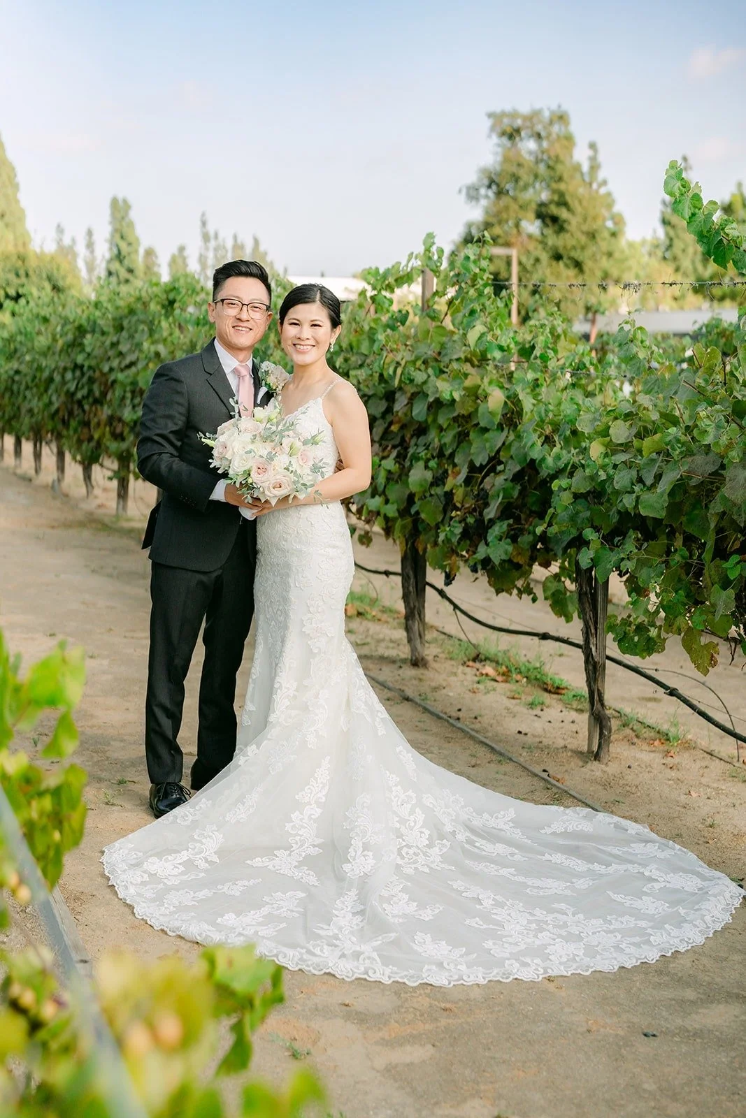 Xuemin and Alex standing together in the vineyard rows