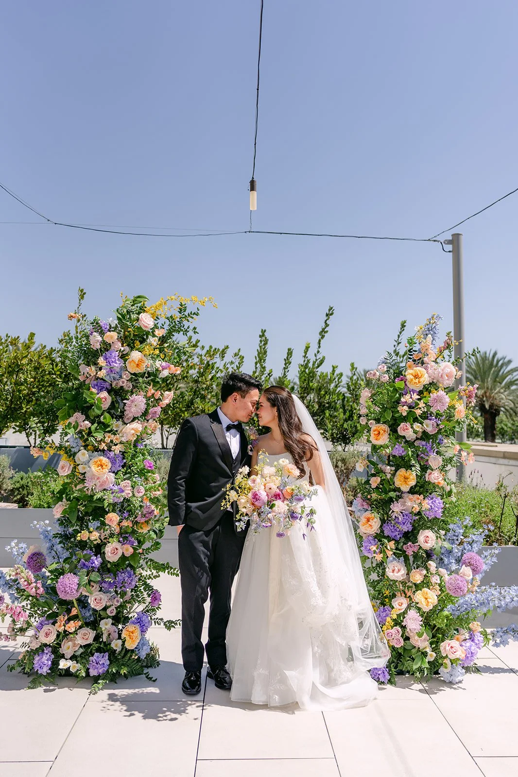 Linh and Hoan kissing between towering pastel floral arches