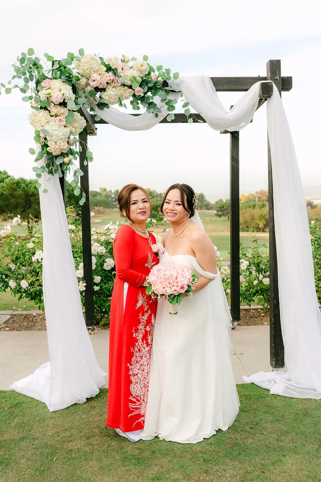 Ivy with a family member in red under the white draped arch
