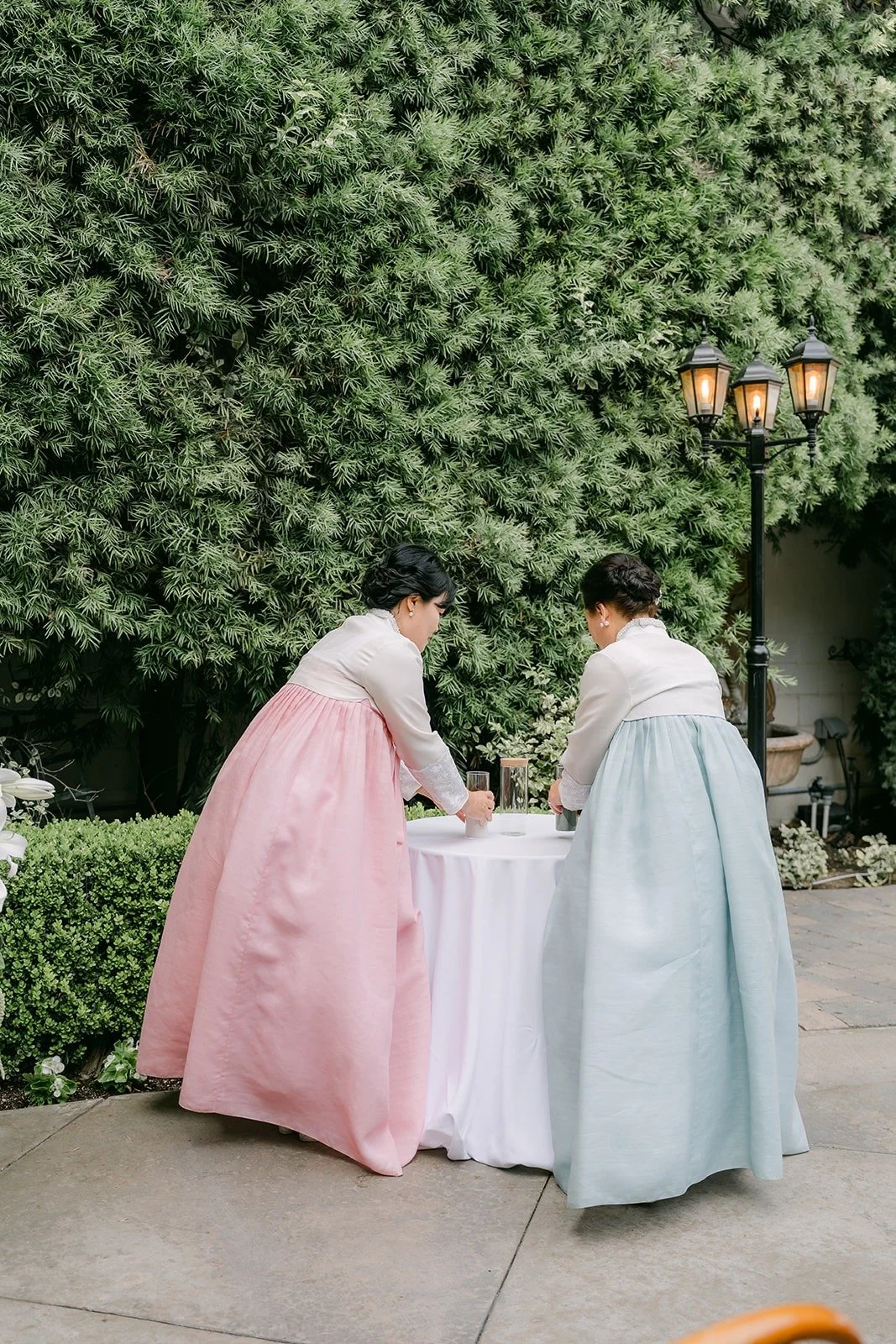 The two family members in hanbok at a small table at the front of the aisle