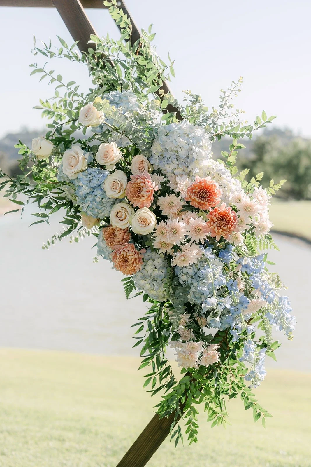 Blush and peach flowers on the hexagon arch overlooking the pond