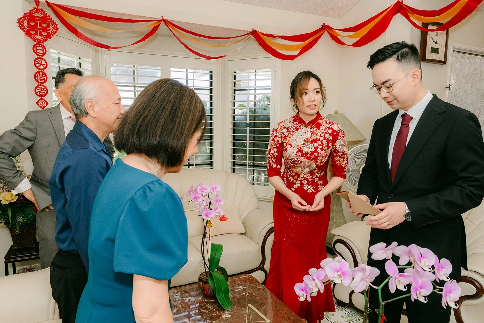 Family gathered around as the bride and groom serve tea at home.