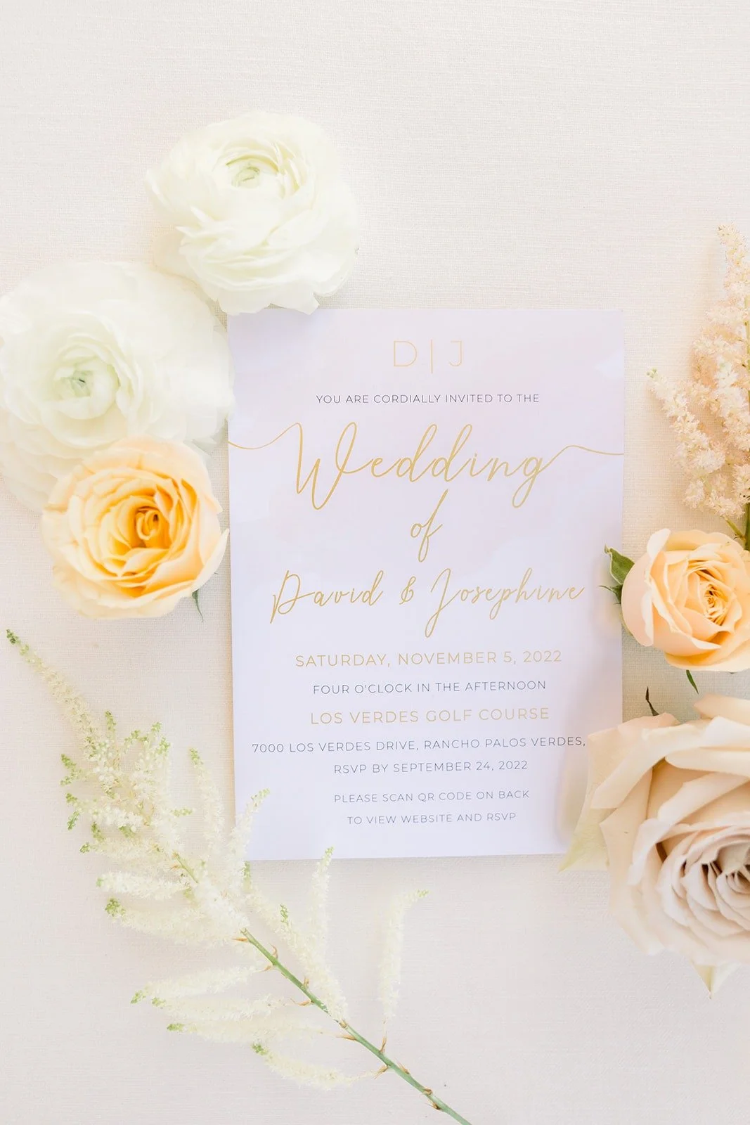 Wedding invitation in soft gold script surrounded by cream roses