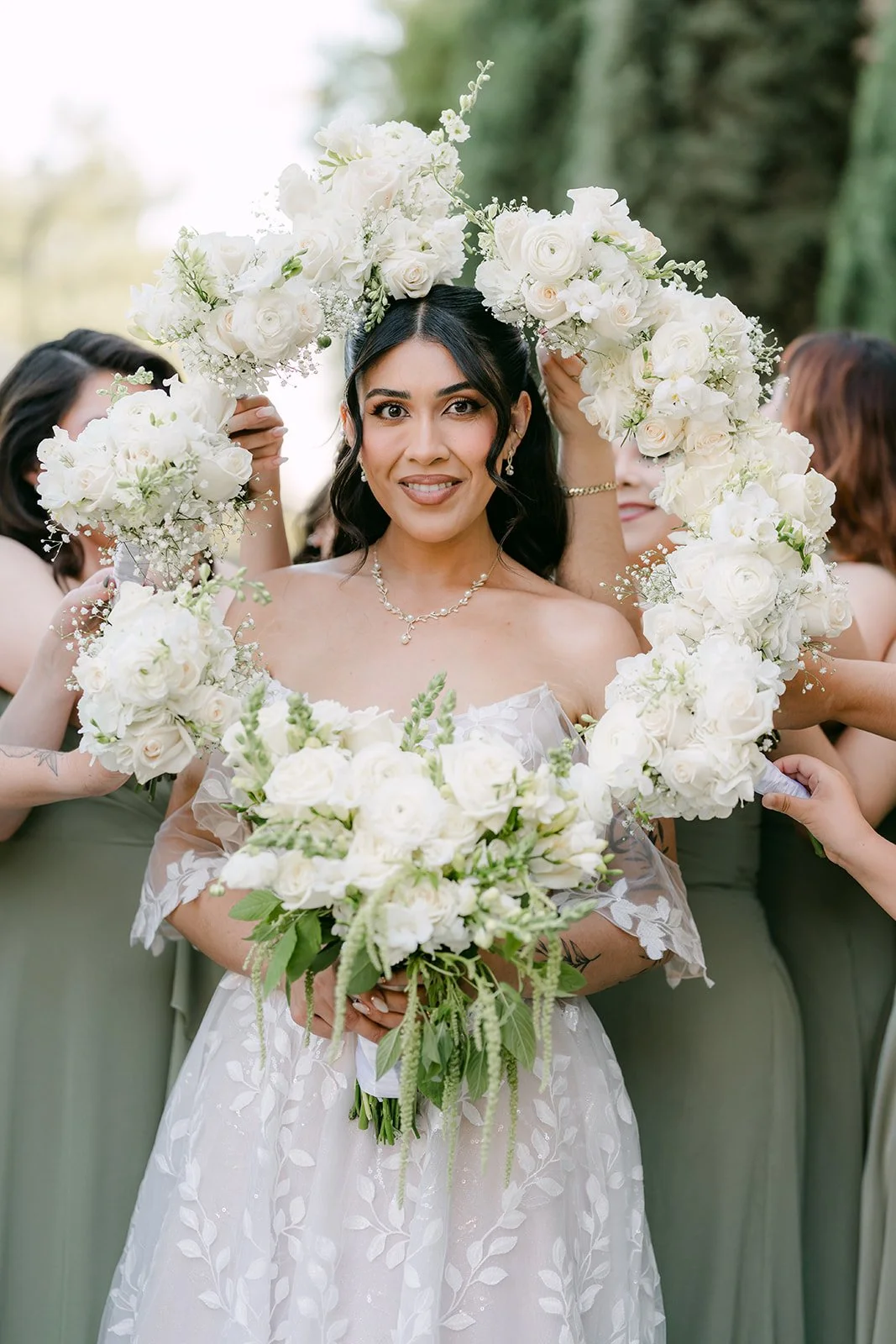 Fernanda holding her white bouquet in front of her bridesmaids.