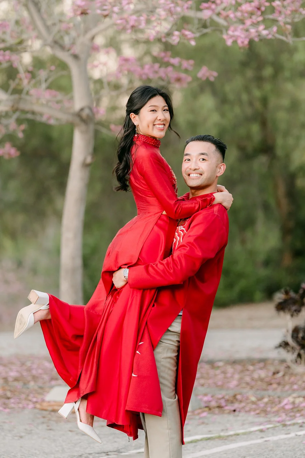 Kim laughing as Vincent lifts her under the blossoming tree.