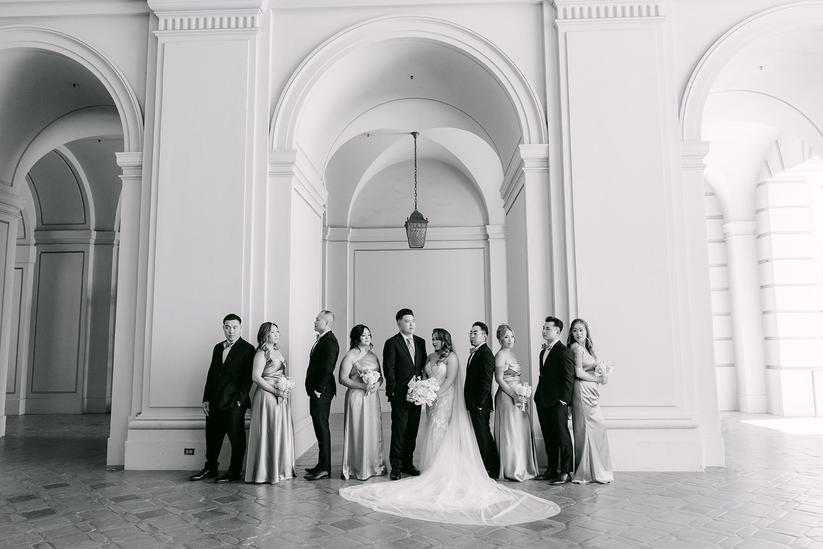 Black and white of the wedding party under the arches at Pasadena City Hall
