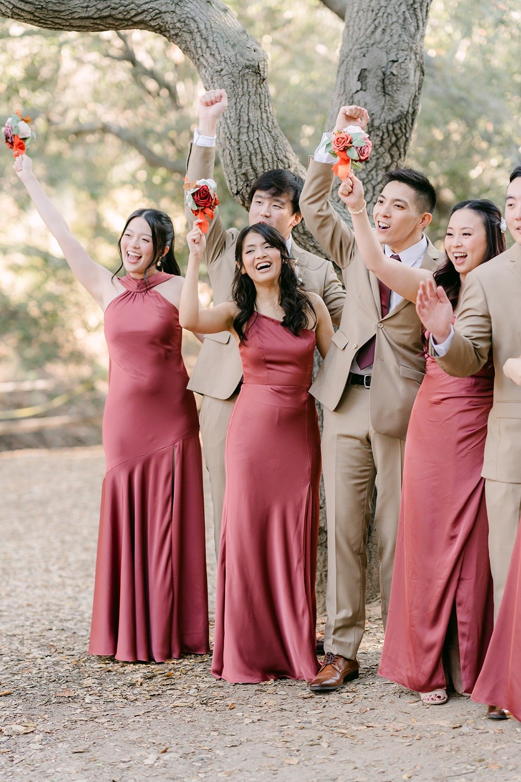 The wedding party cheers with bouquets in the air