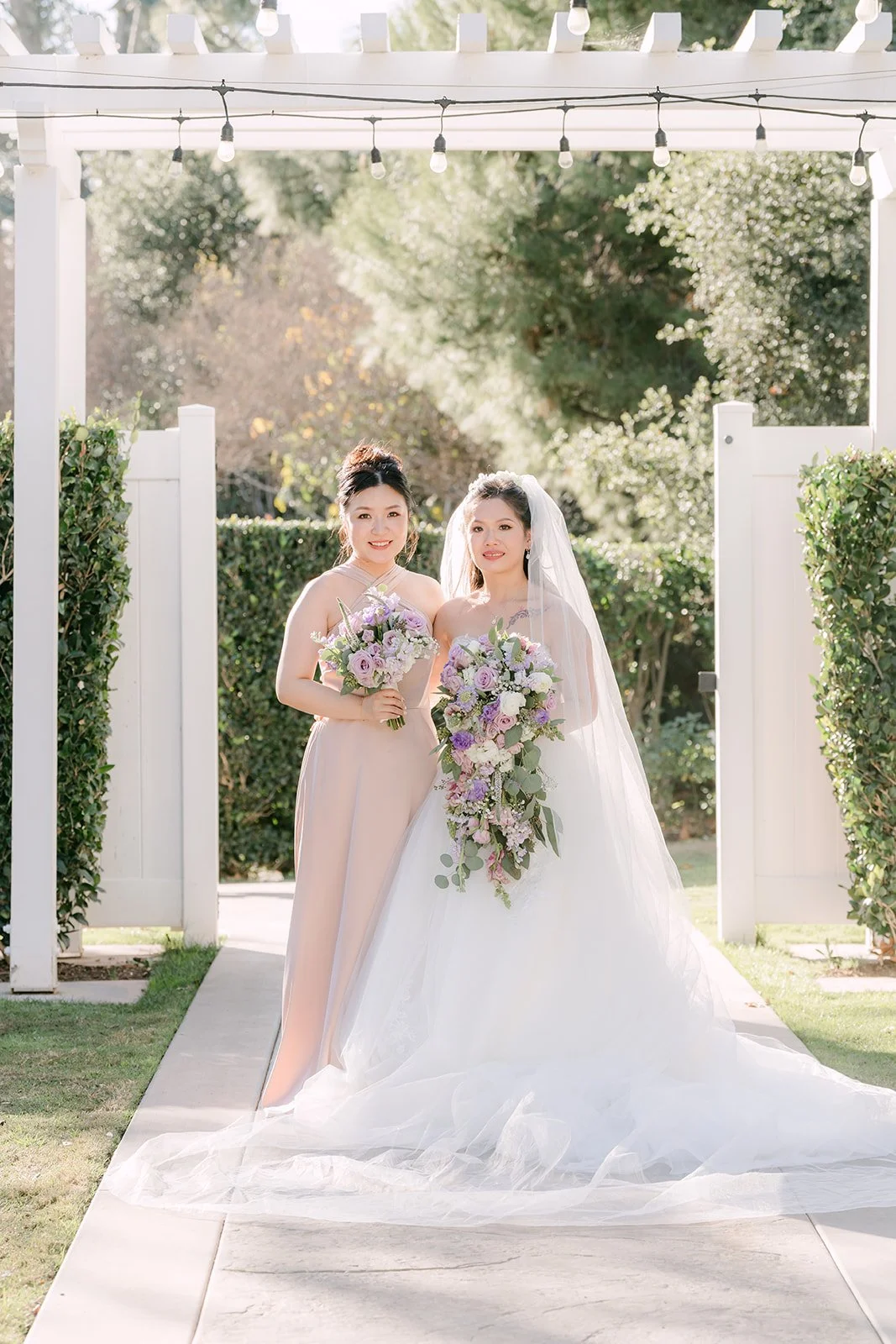 Kate and a bridesmaid under the white pergola.