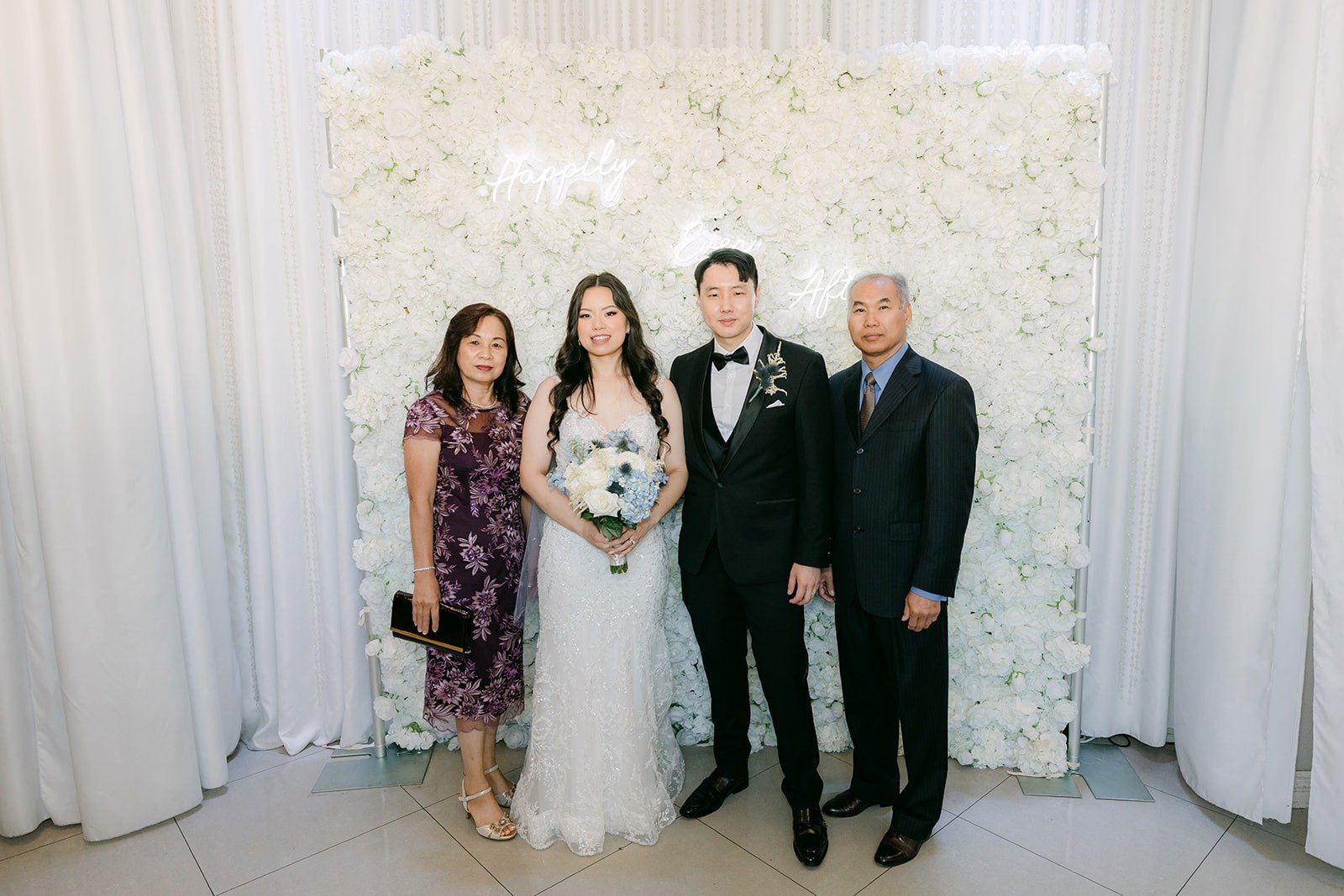 Emily and James with family at the flower wall