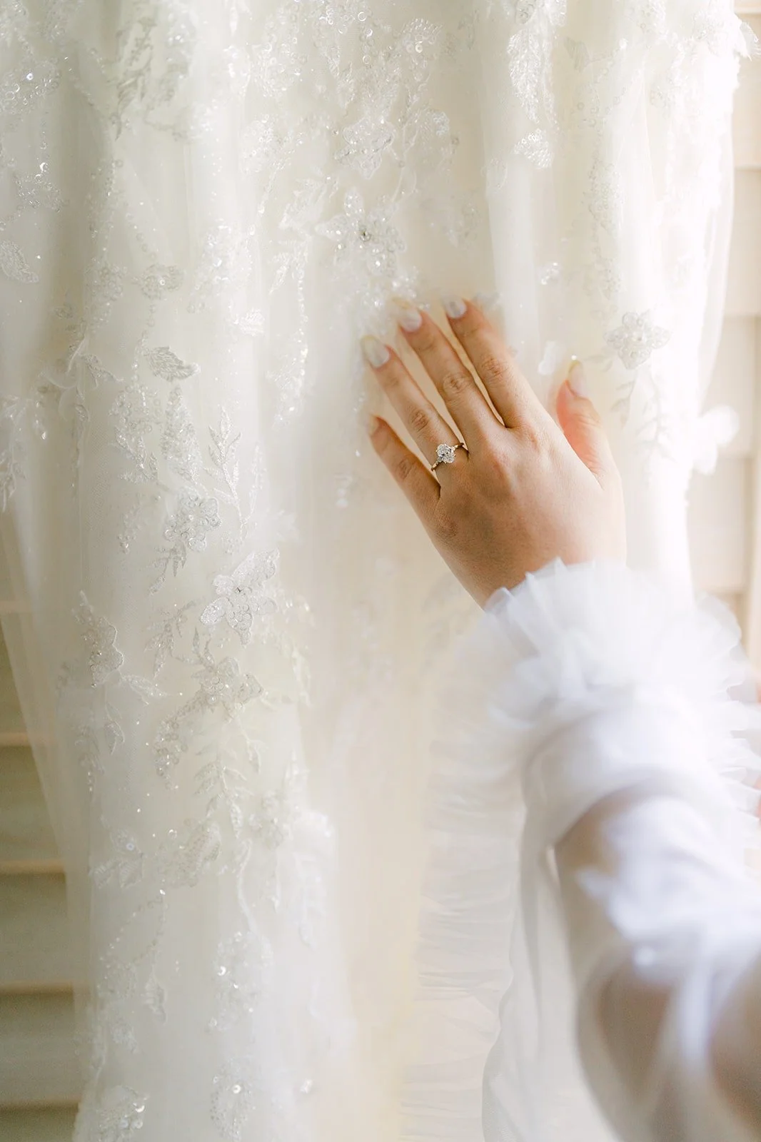 Joanne's hand touching the beaded lace of her gown