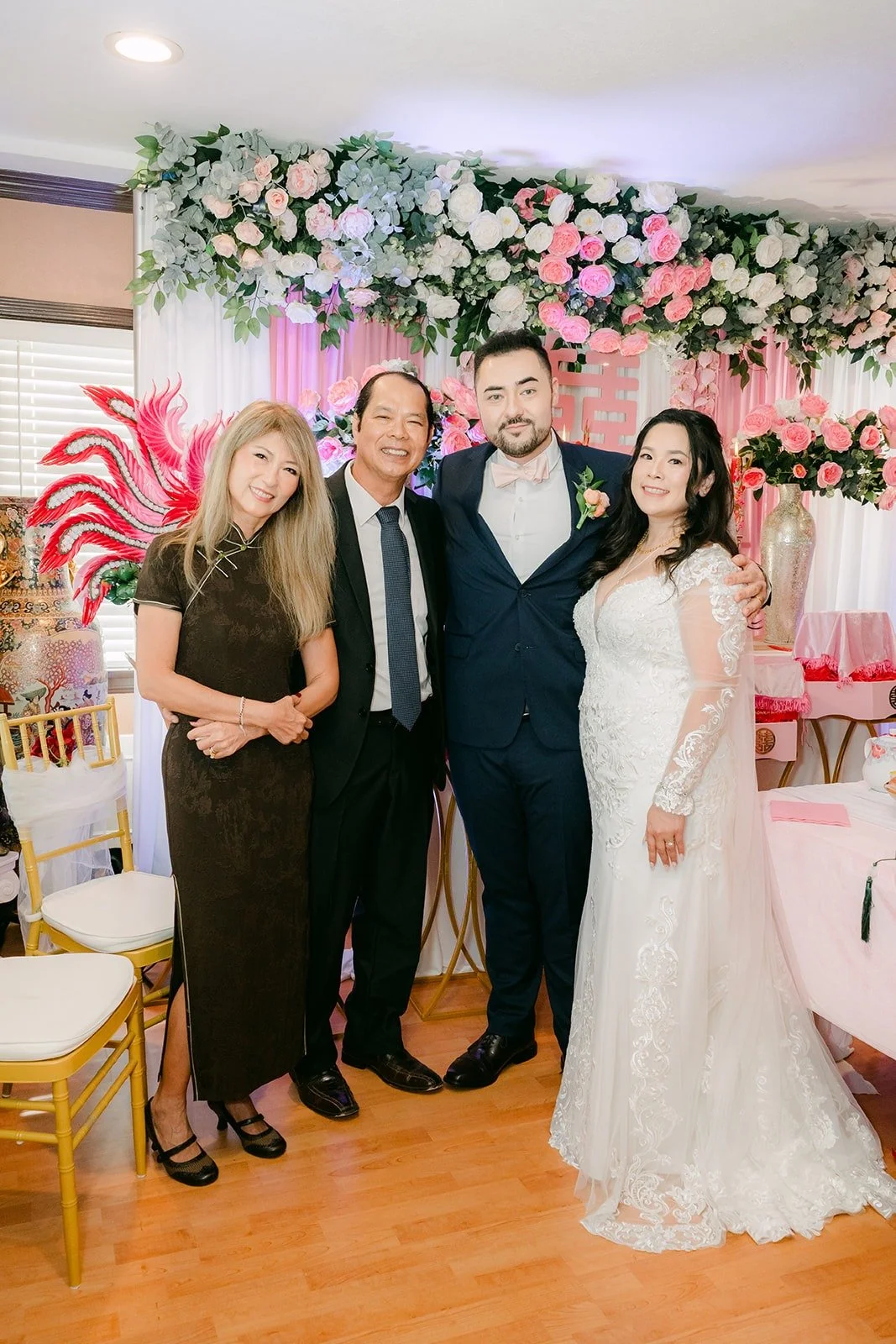 Amy and James with family in front of the pink tea ceremony backdrop