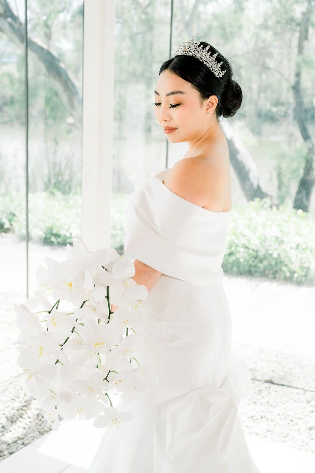 Jacinda in profile with her orchid bouquet beside a glass wall
