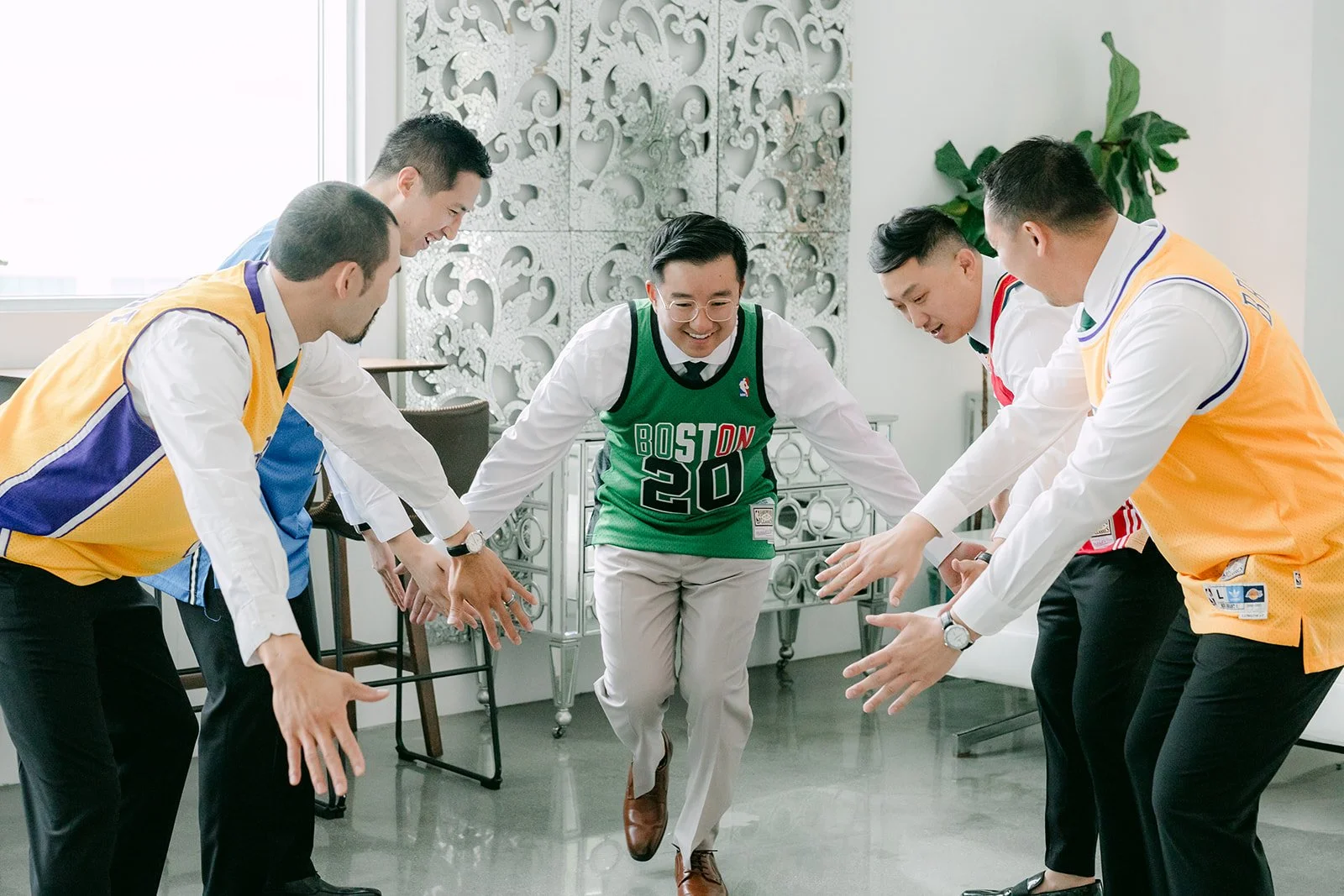 Groomsmen in jerseys cheering as Ricky jumps in the middle