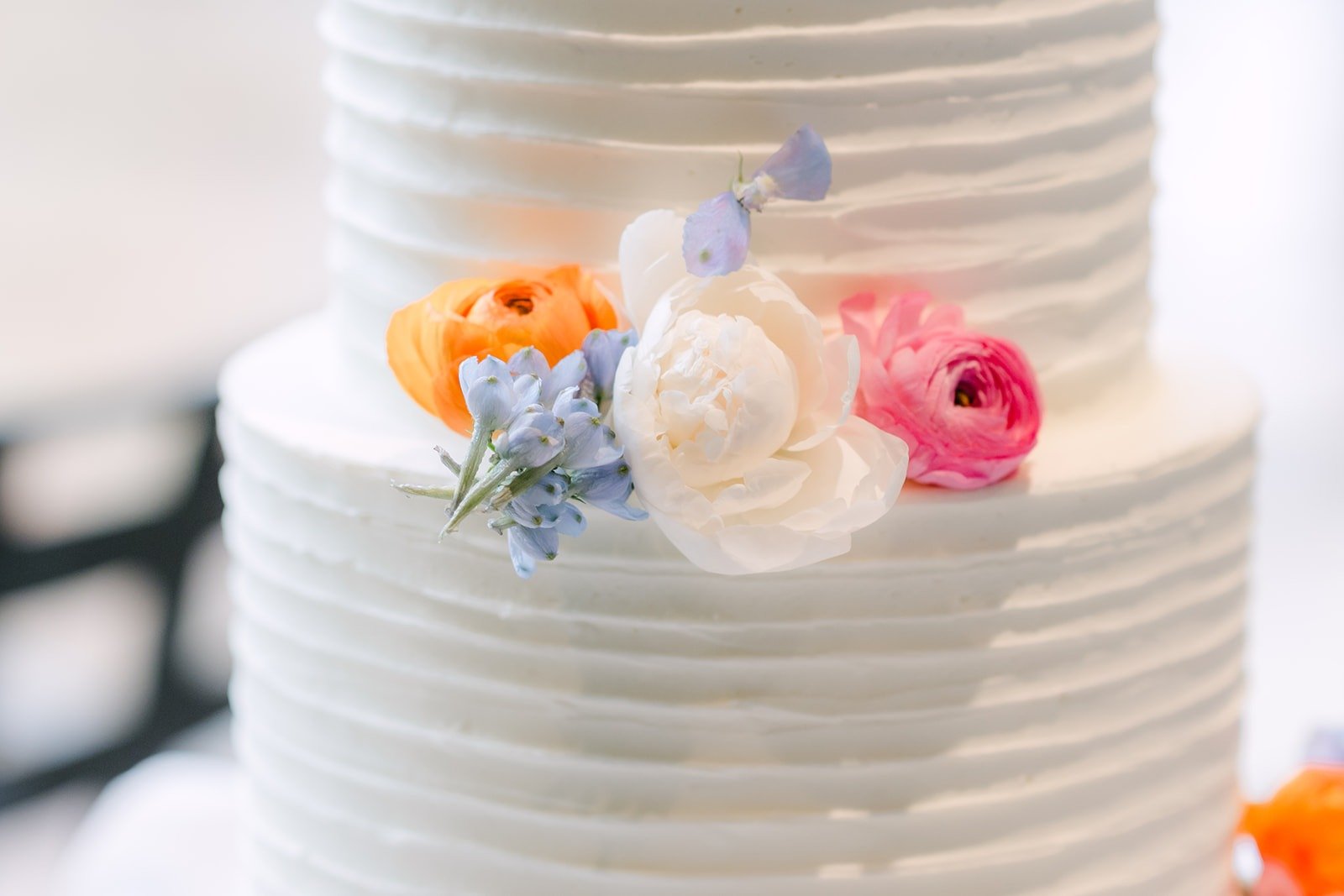 A close up of the textured cake with orange, pink and blue flowers