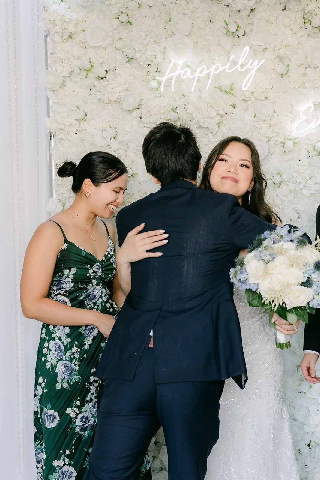 A guest hugging James at the flower wall