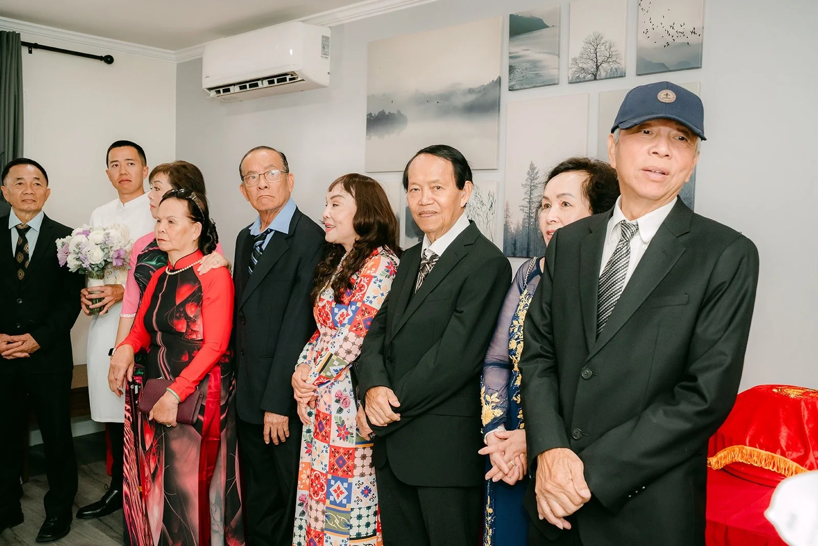 Family members in ao dai and suits watch the tea ceremony begin
