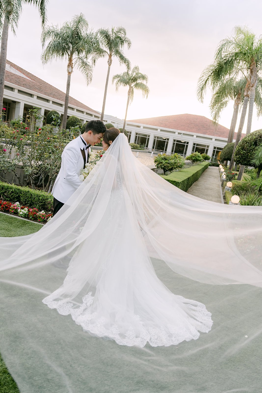 Jenny's cathedral veil spread across the garden path as Ryan kisses her.