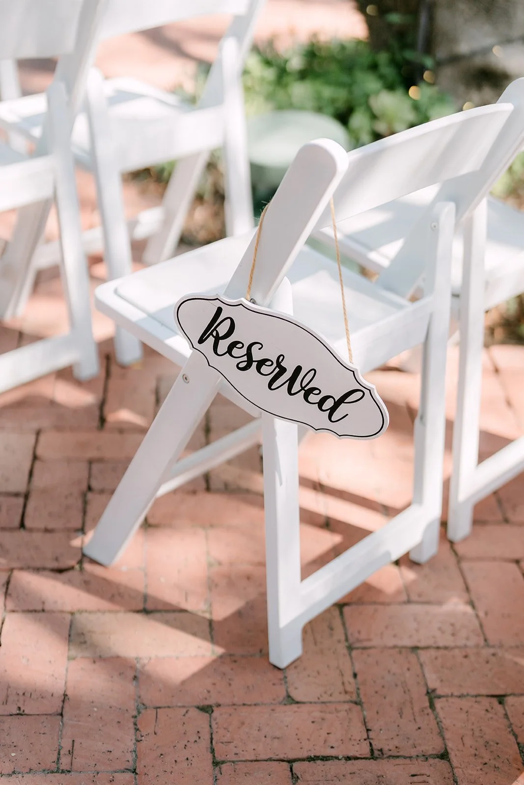 Reserved sign on a white folding chair along the brick aisle, photographed by One and Only Production