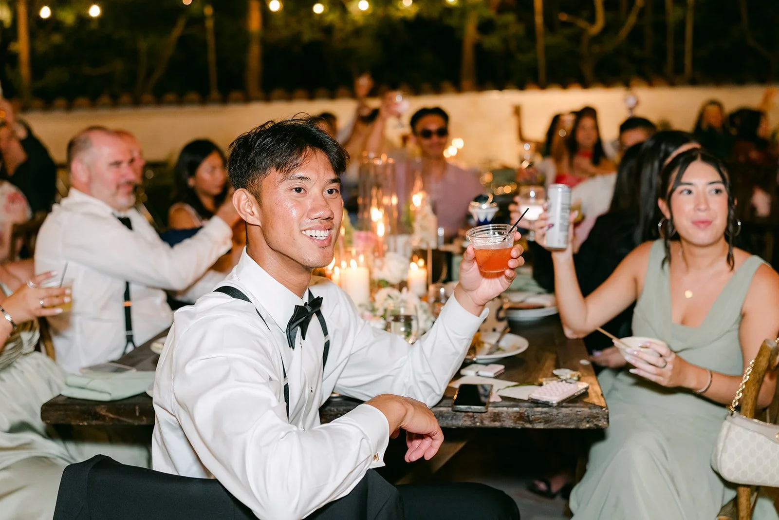Caryl raising a glass during the toasts as guests laugh.