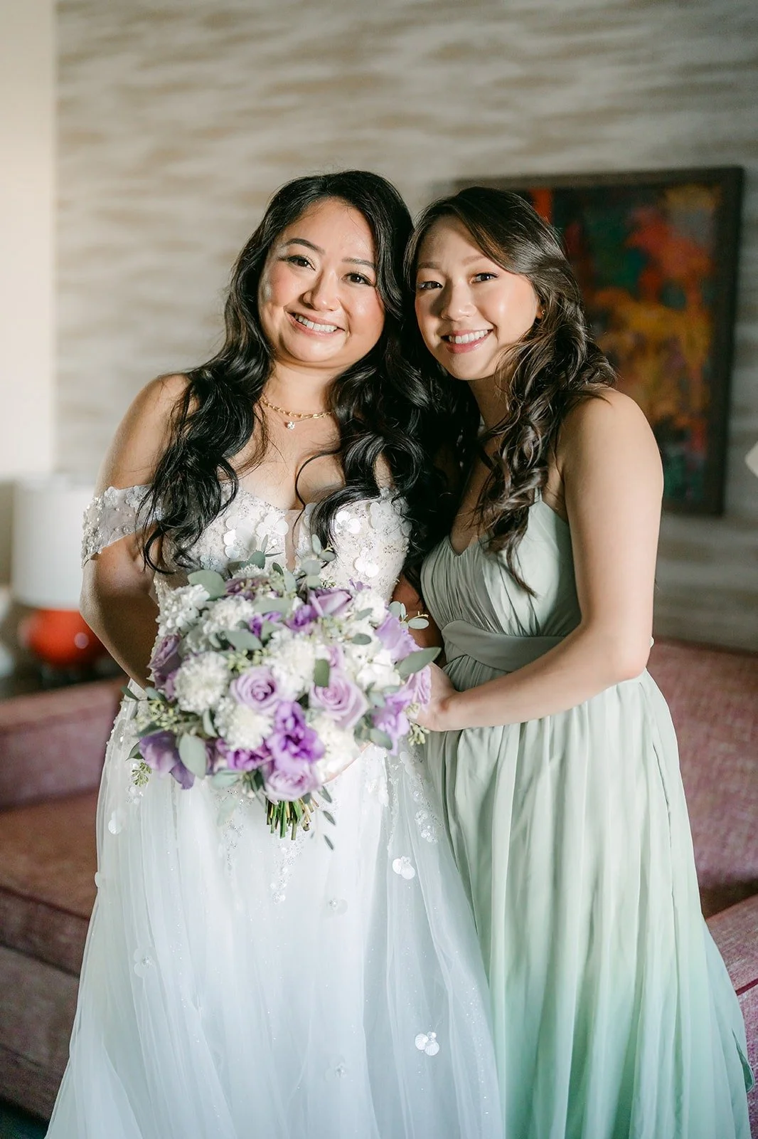 Jennifer shares a laugh with a bridesmaid while holding her lavender and white bouquet