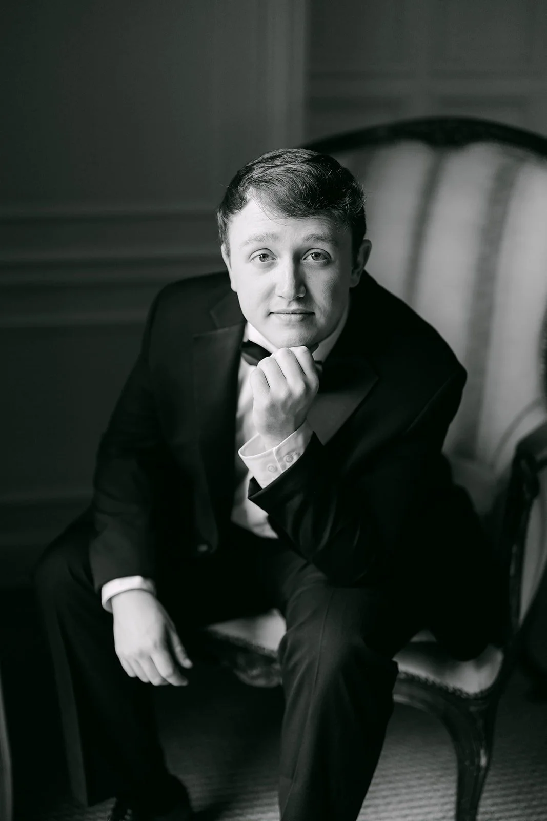 A black and white portrait of Matthew relaxing in an armchair
