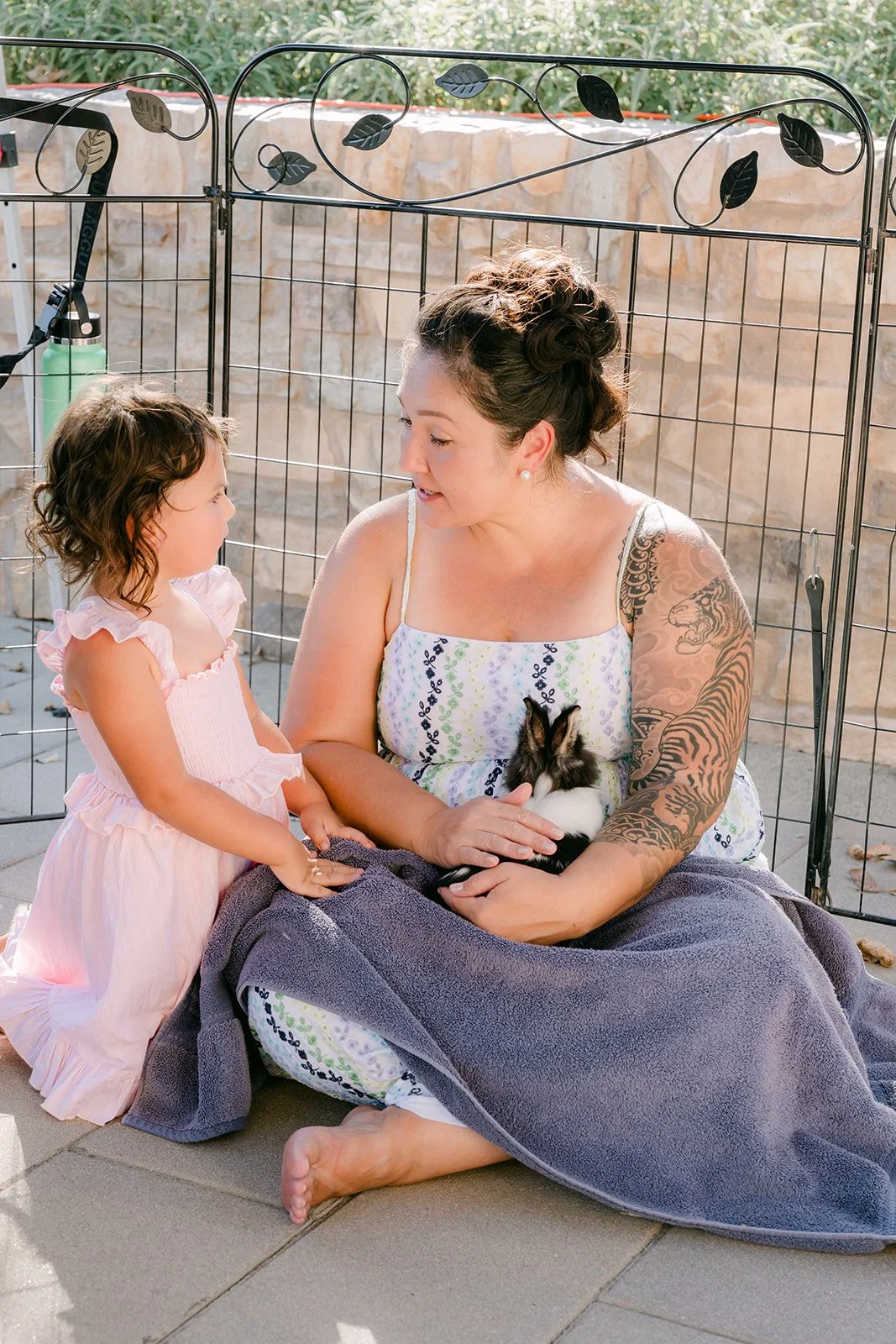 A guest and a little girl sitting together near the animal pen.