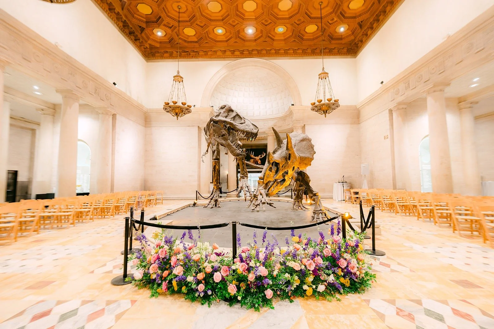 The dinosaur display in the Grand Foyer ringed with ceremony florals