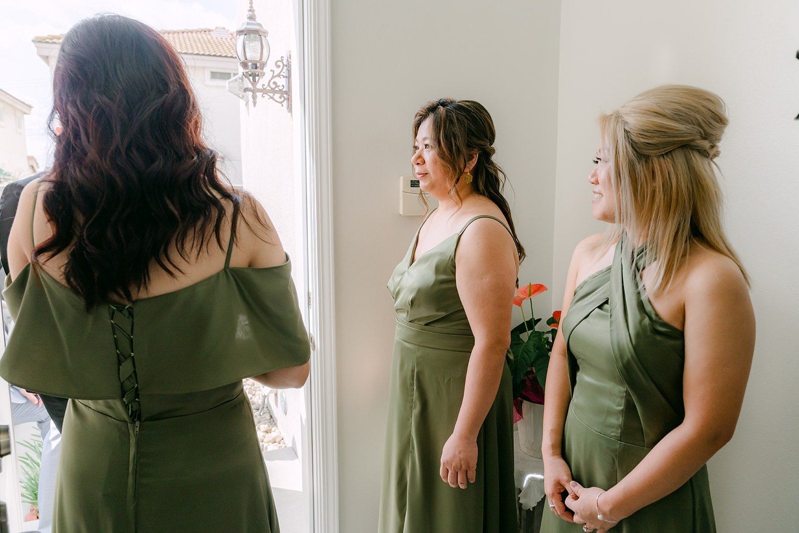 Eunice's bridesmaids in olive green dresses waiting to run the door game