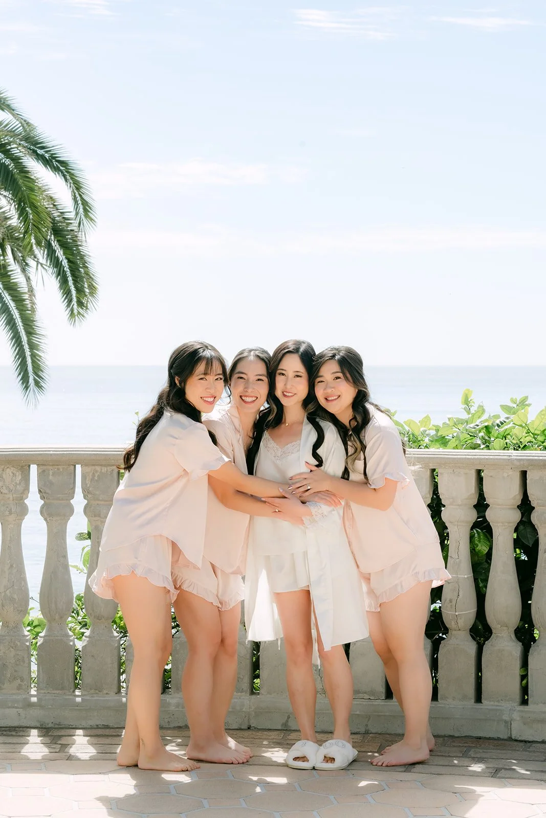 Bride hugging her bridesmaids in matching pajamas on the balcony