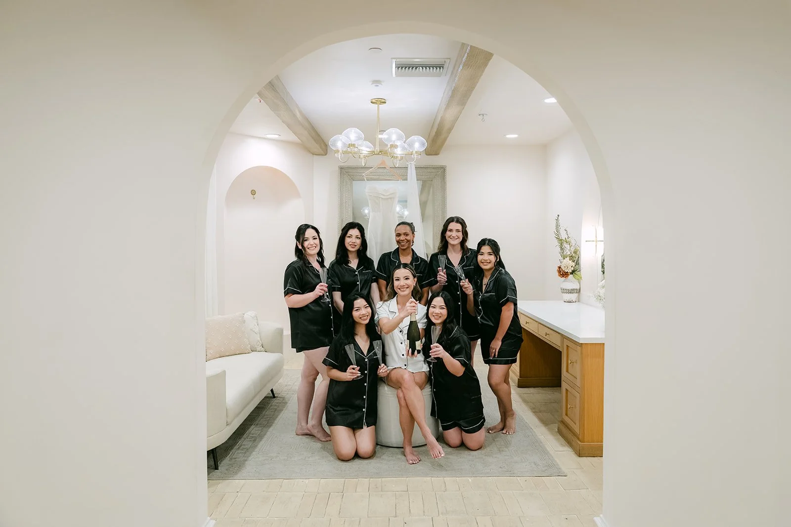 Bridesmaids in black satin robes posing with the bride in the bridal suite