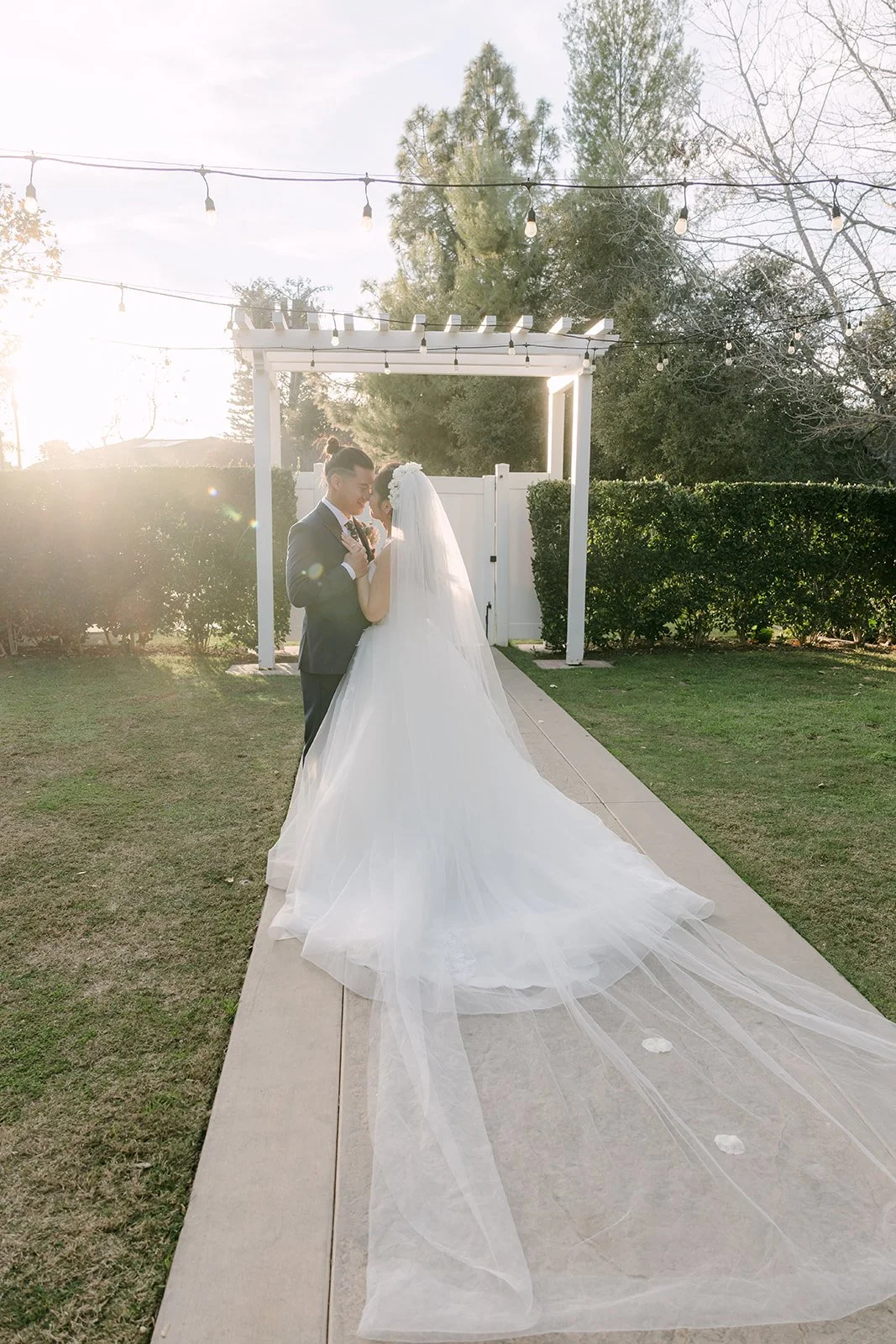 Kate's veil trailing down the aisle toward the pergola, photographed by One and Only Production.