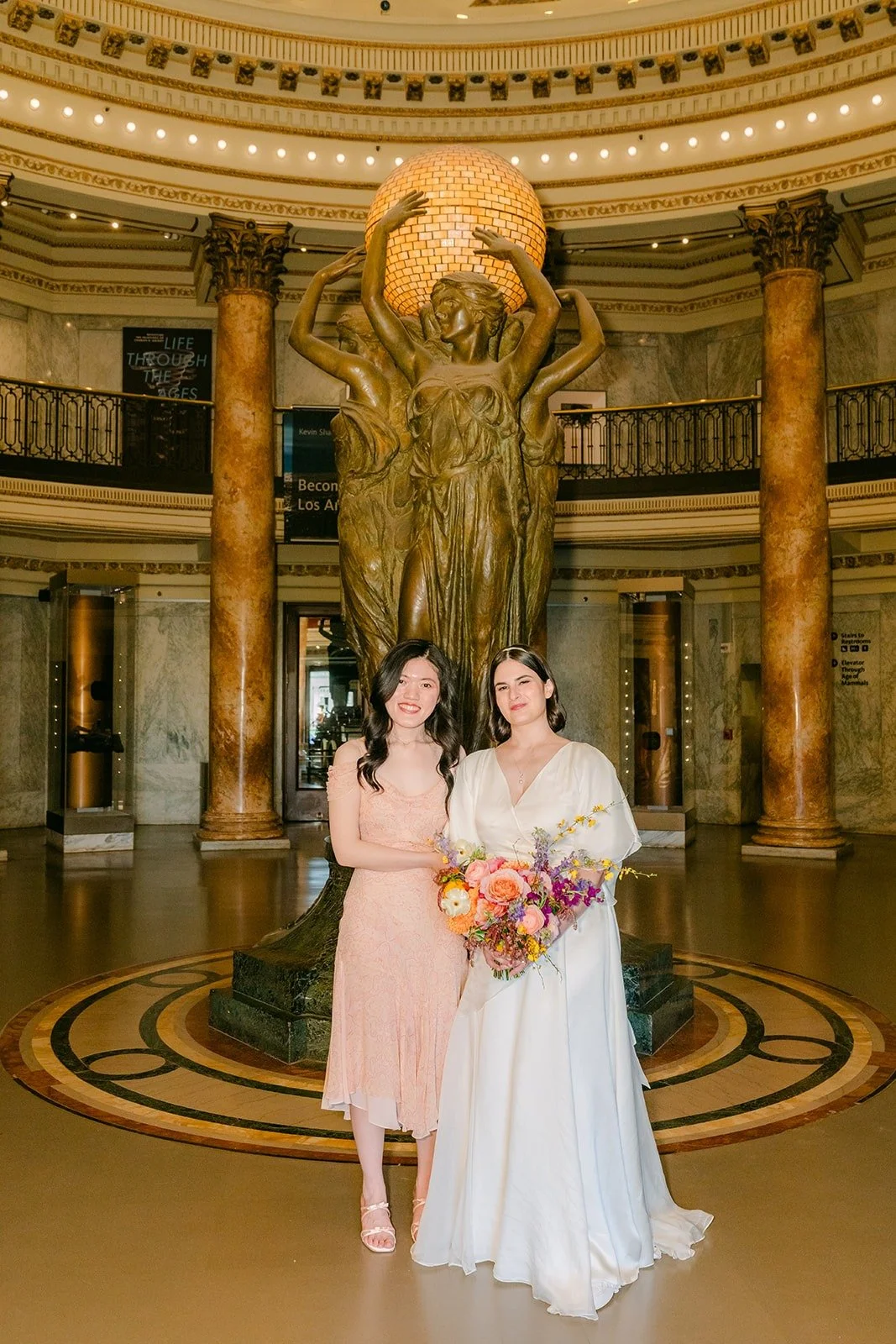 Jessie with a bridesmaid in blush beside the Rotunda statue