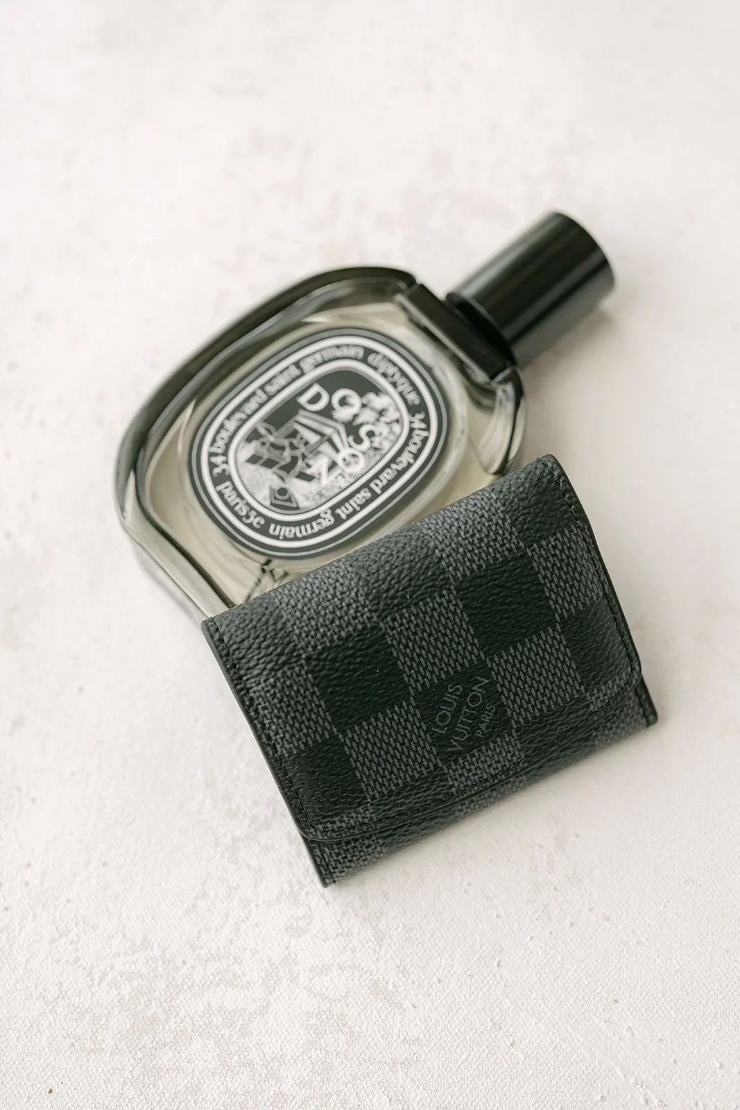 A black bottle of cologne laid on a dark patterned card