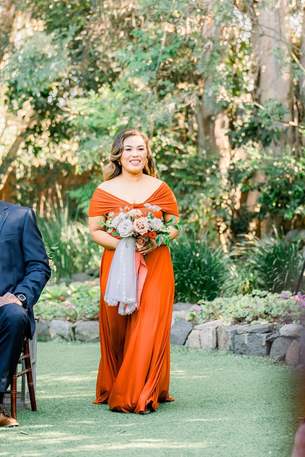 A bridesmaid smiling as she walks down the aisle