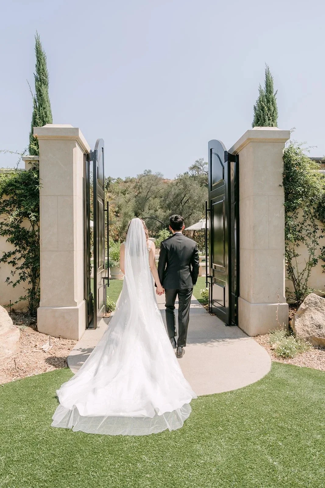 Couple walking through the tall stone pillared gates at Monte Bella