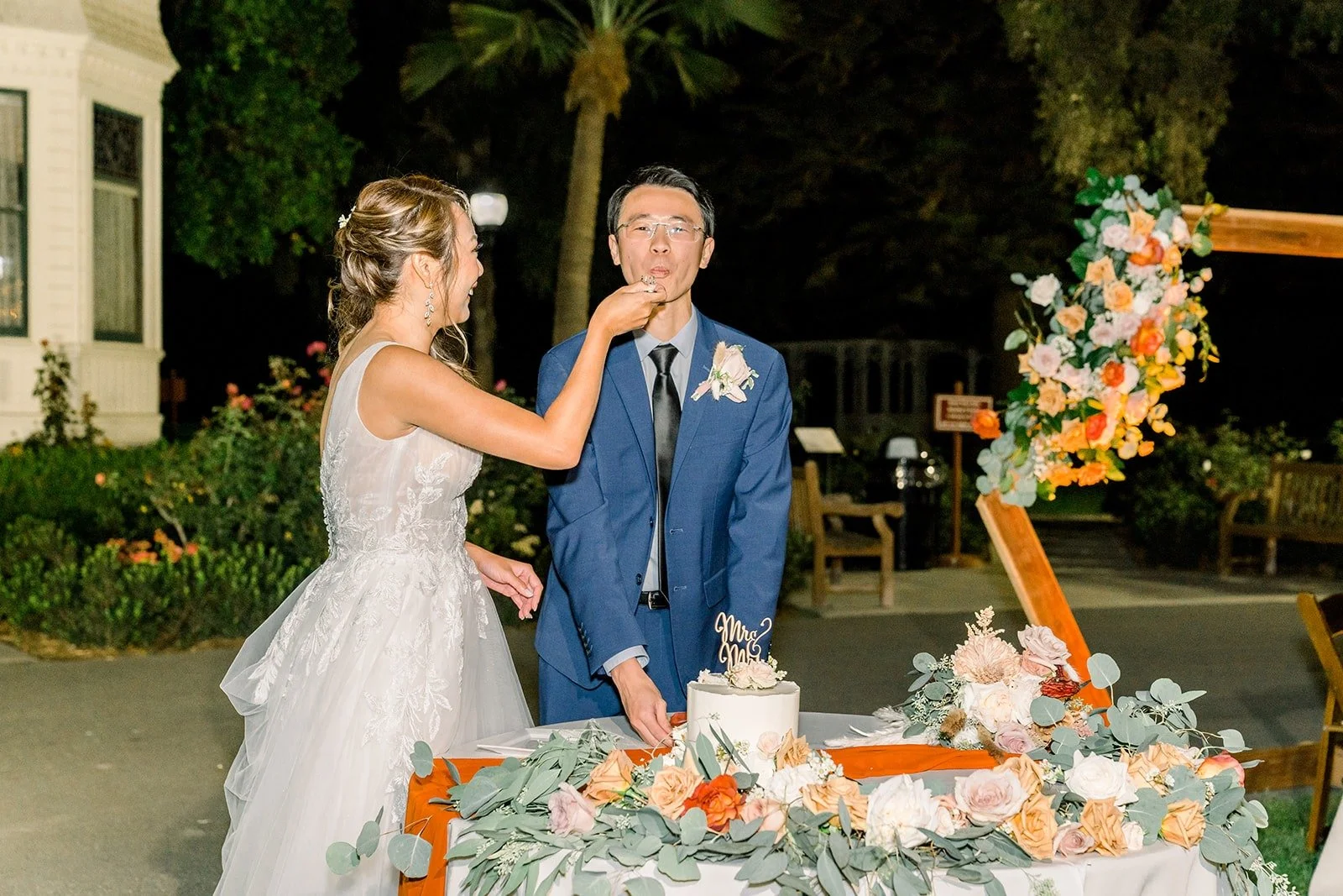 Ariel and Alex sharing a bite of cake, photographed by One and Only Production