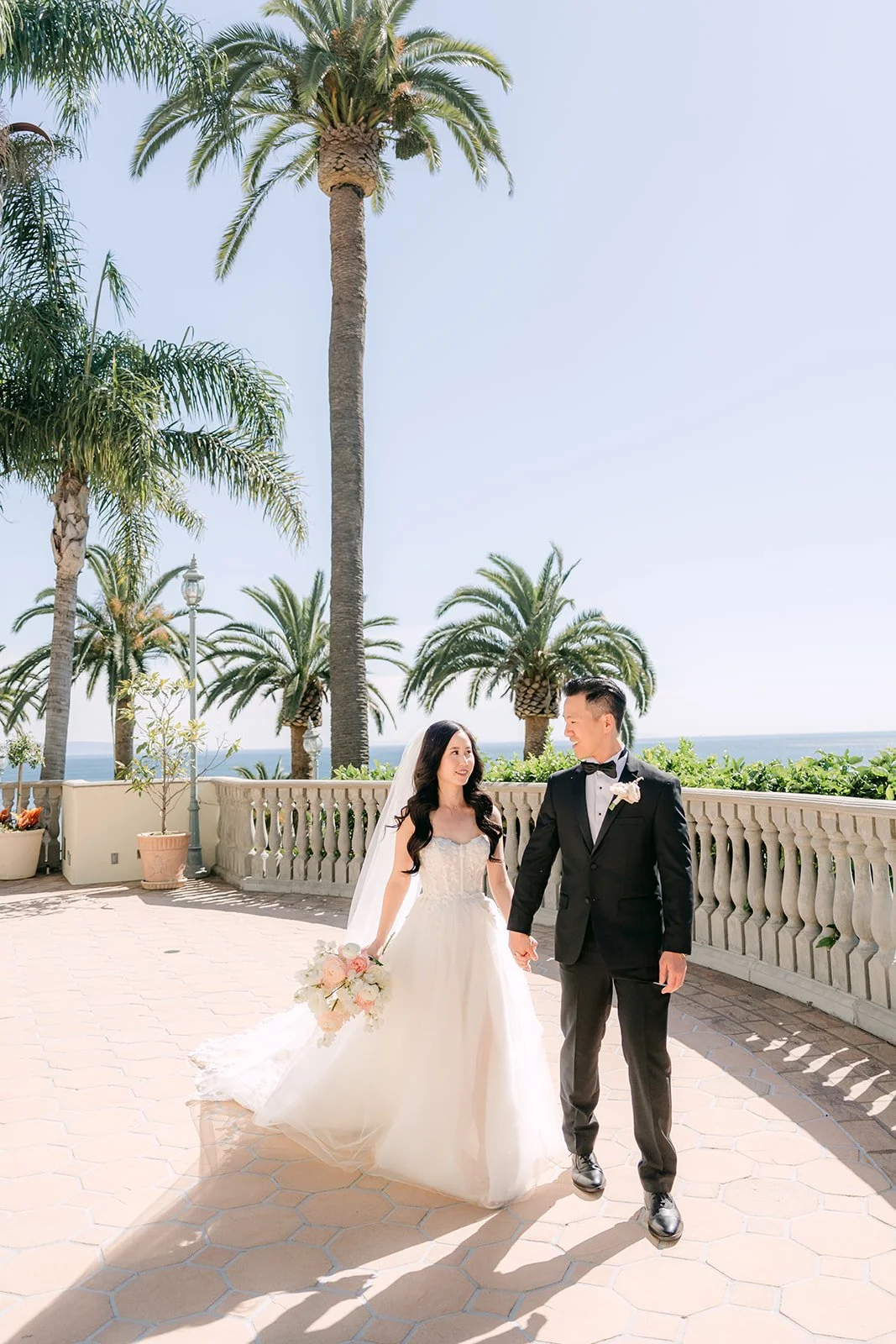 Bride and groom walking hand in hand under the palm trees