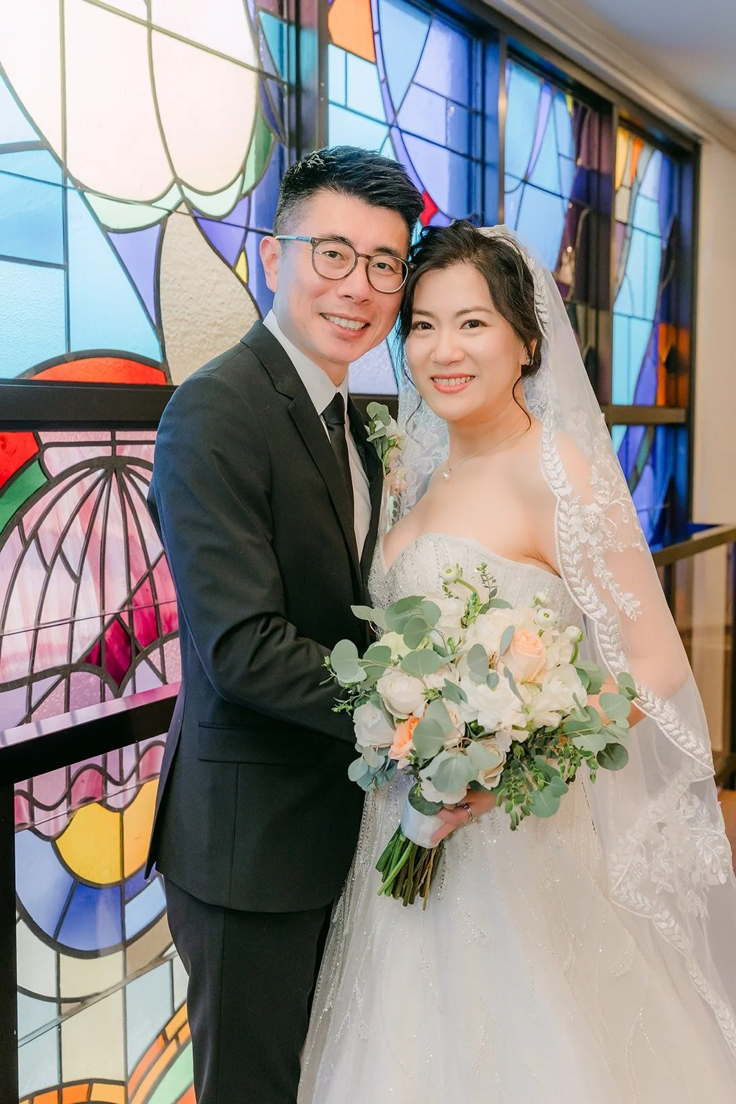 Eunice and Eric smile together by the Rainbow Glass Wall