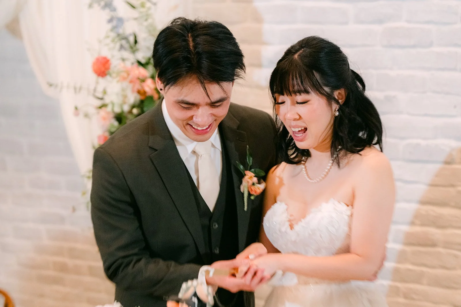 Vivian and Alex laughing as they cut the cake, photographed by One and Only Production