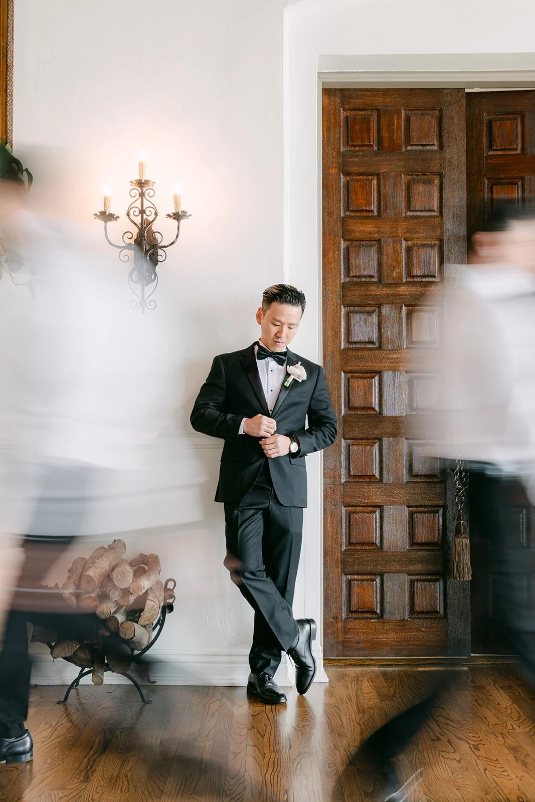 Groom standing still as his groomsmen move past in motion blur