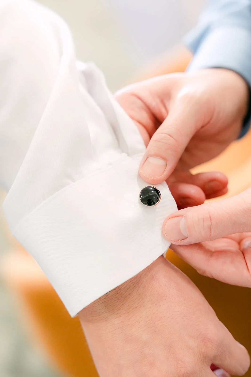 Close up of a cufflink being fastened on Jay's sleeve