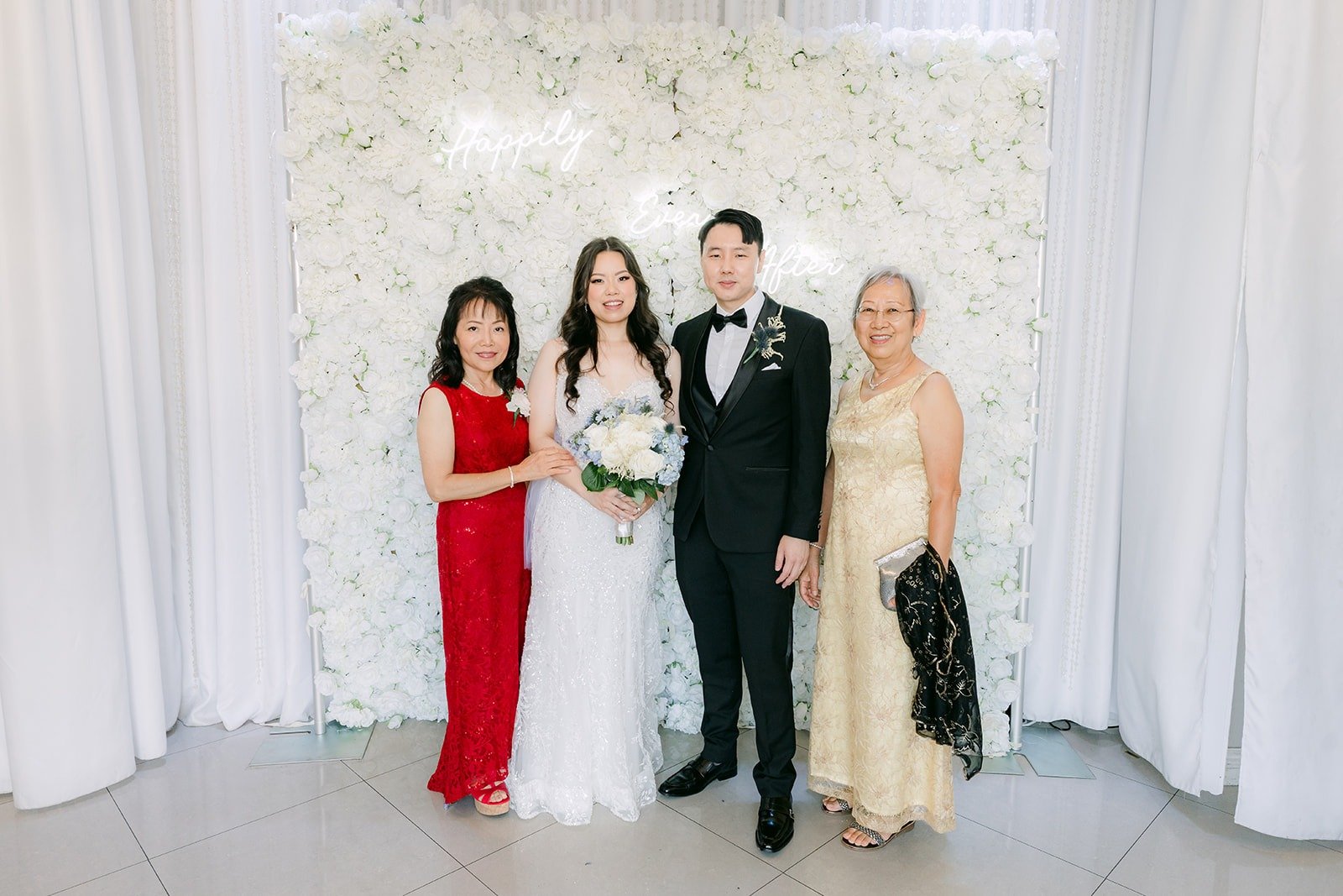 Emily and James welcoming guests by the floral backdrop