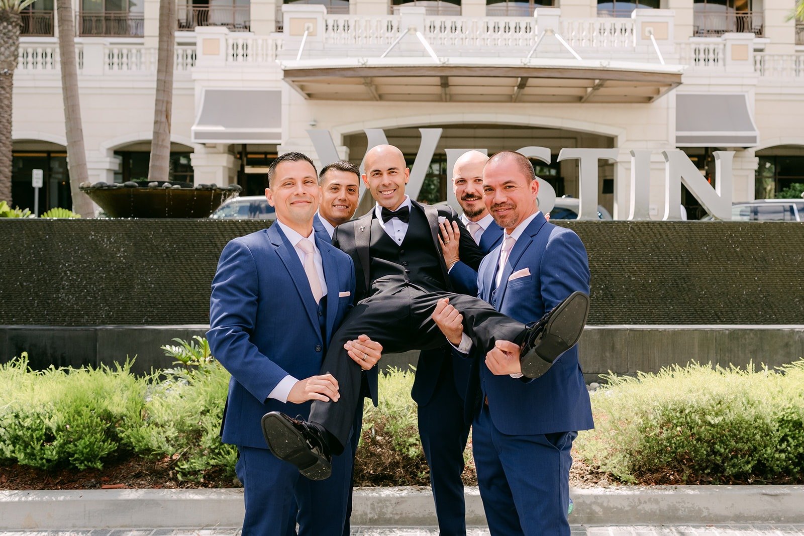 The groomsmen lift Daniel in front of the Westin