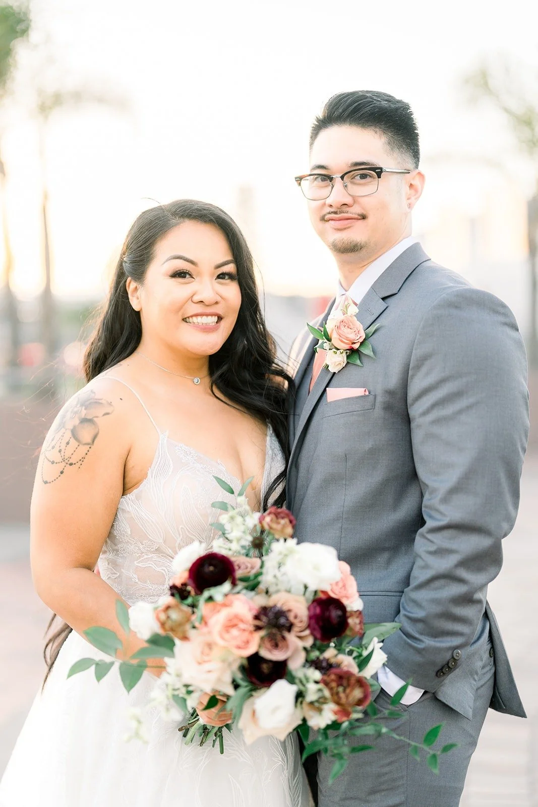 Betsy and Mikey smile with her bouquet at sunset