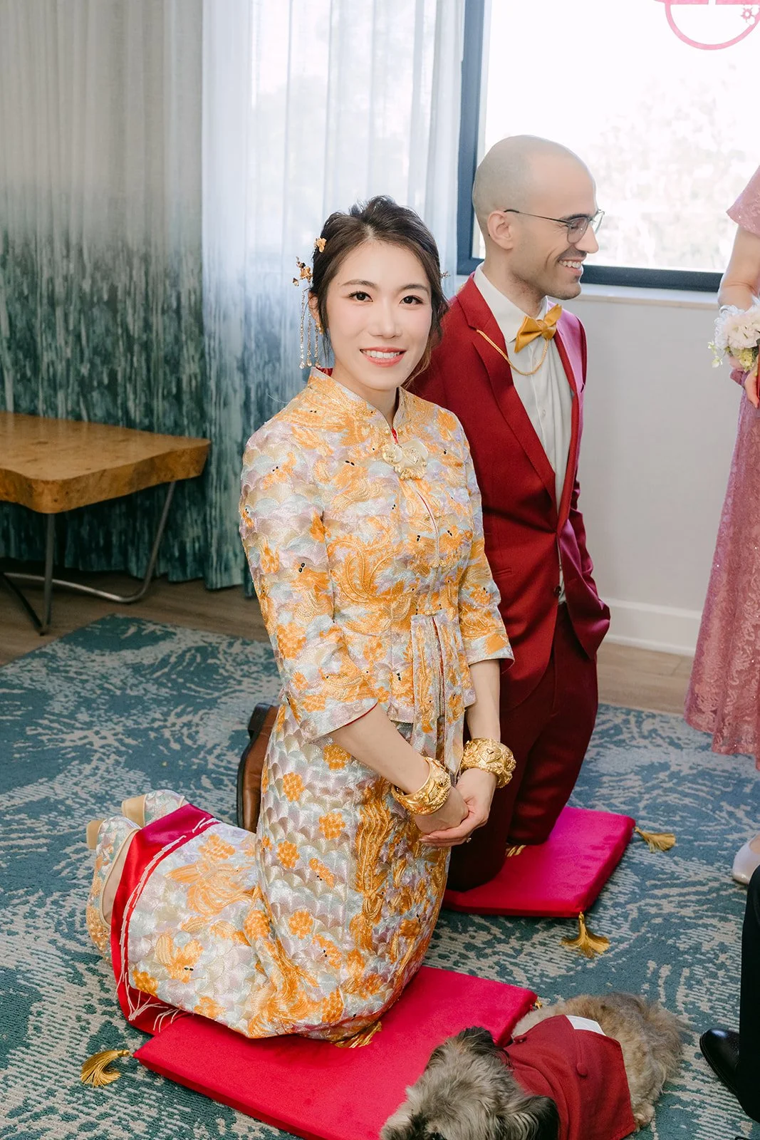 Christie kneeling on a red cushion during her family's tea ceremony.