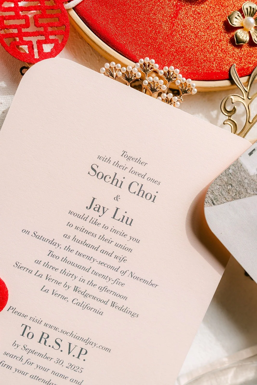 Sochi and Jay's wedding invitation styled with a red embroidered fan