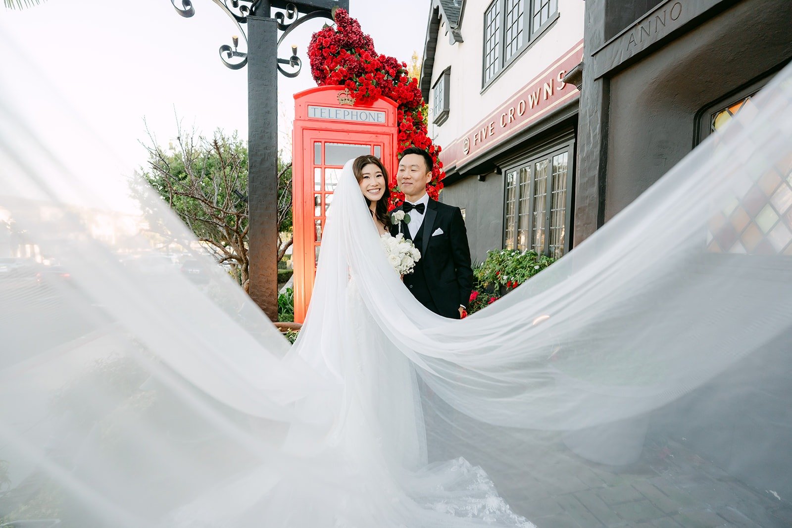 Valerie's veil billowing across the brick path as she and Jason stand by the red phone booth at Five Crowns