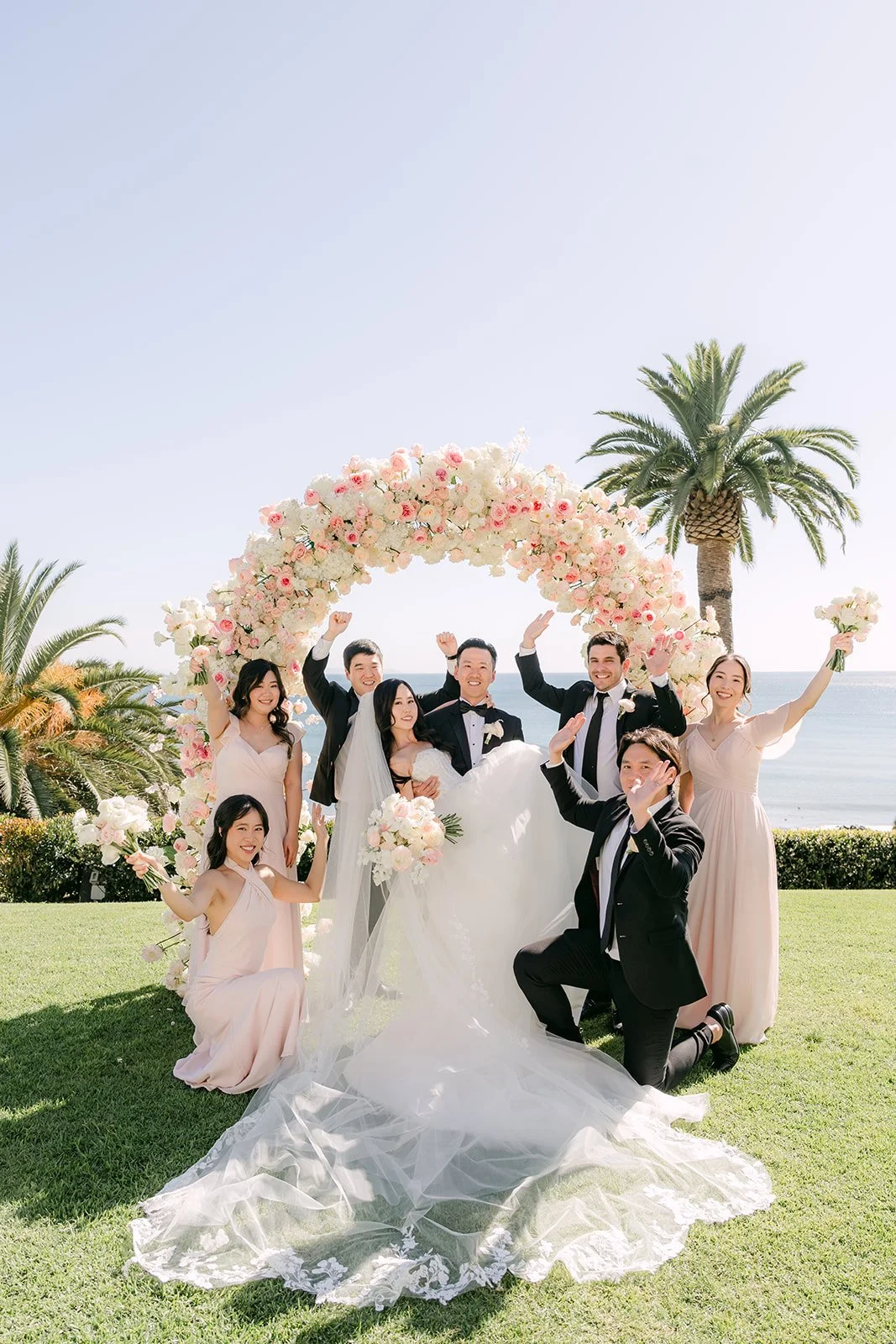 Wedding party cheering in front of the ceremony arch