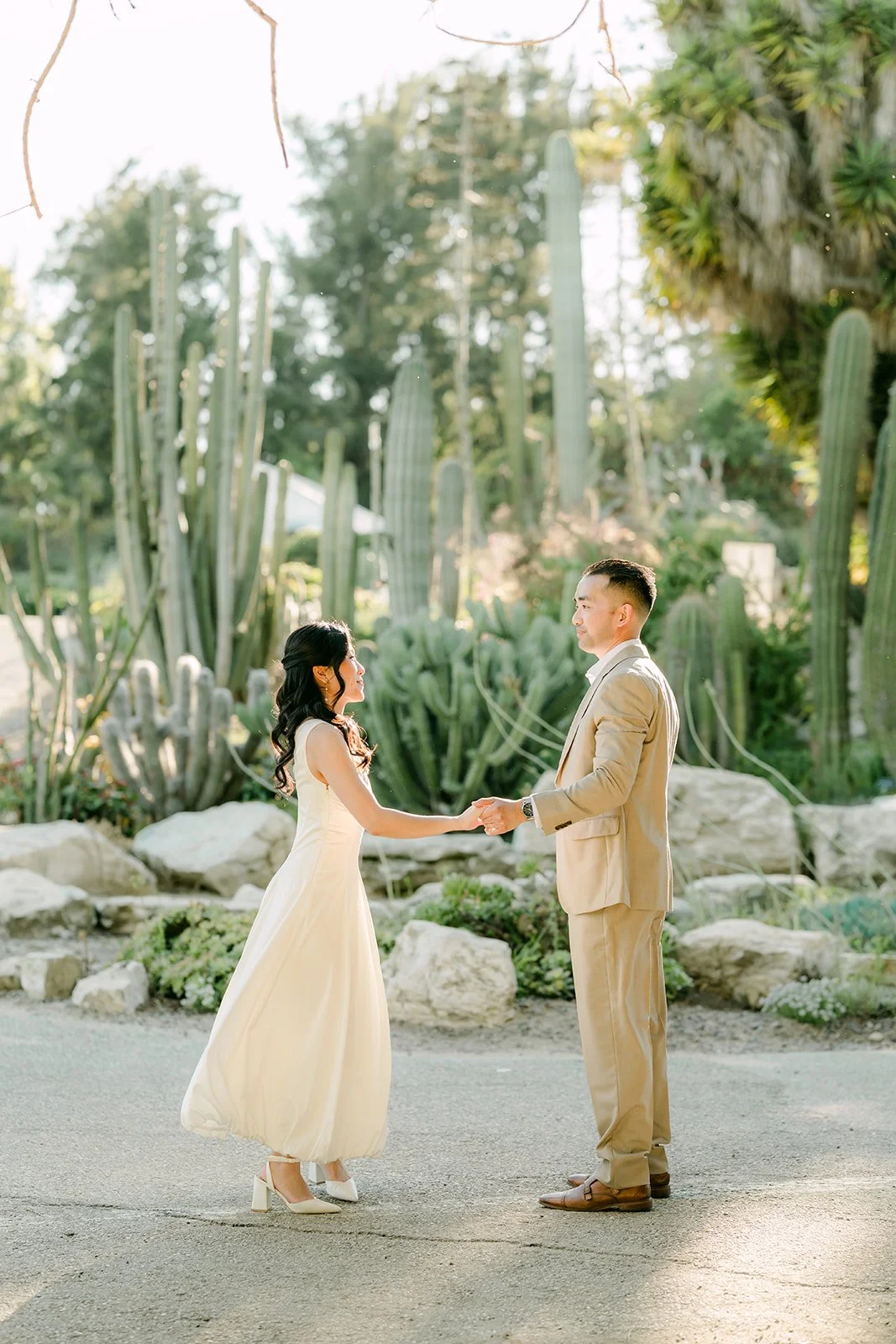 Kim and Vincent reaching for each other's hands on the cactus garden path.